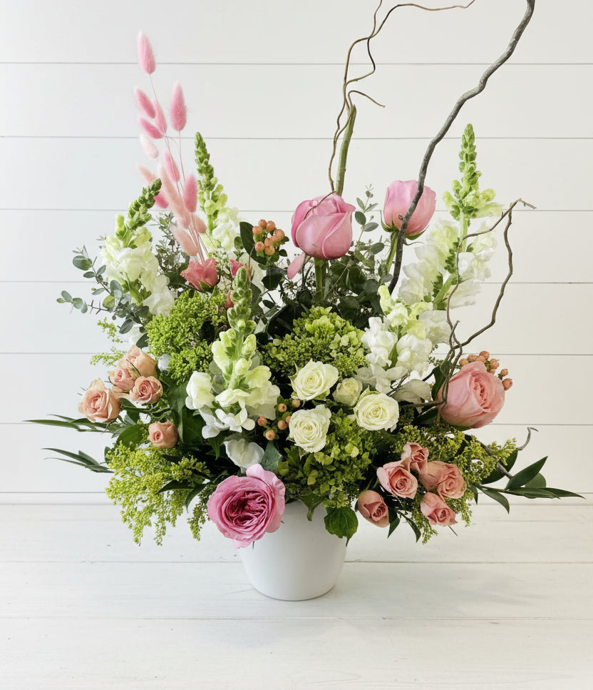 Floral arrangement with pink and white flowers in a white vase on a light background