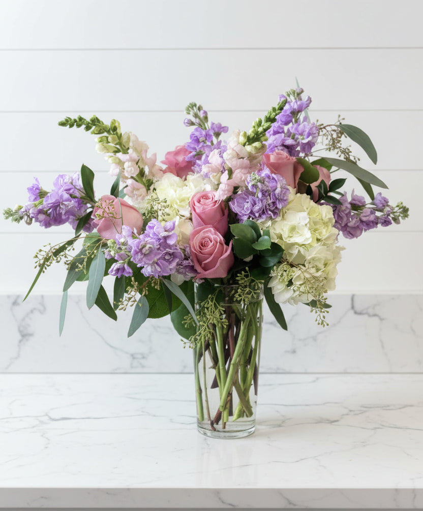 Bouquet of flowers in a clear vase on a light surface with a light gray background