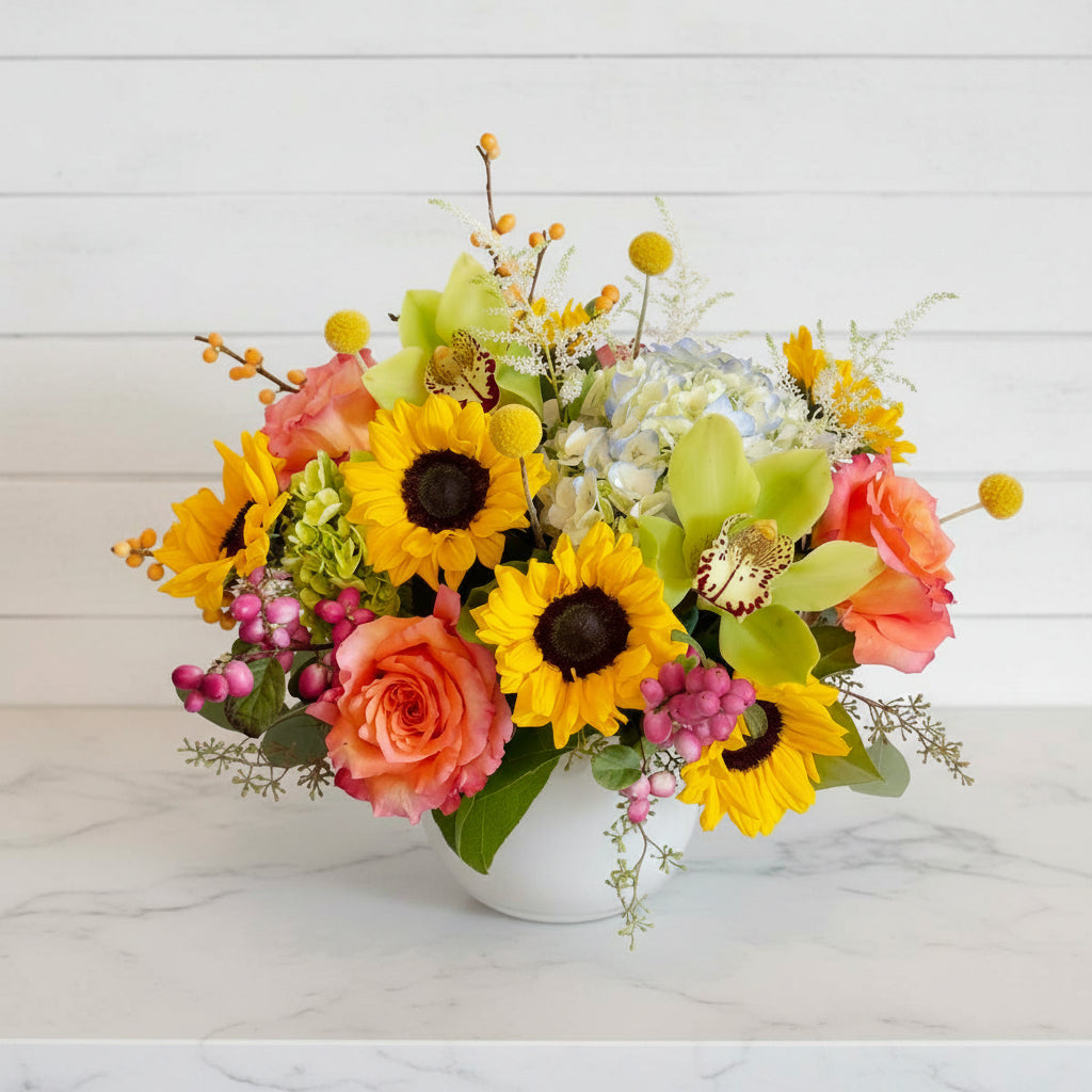 Colorful flower arrangement with sunflowers, roses, and orchids on a white background