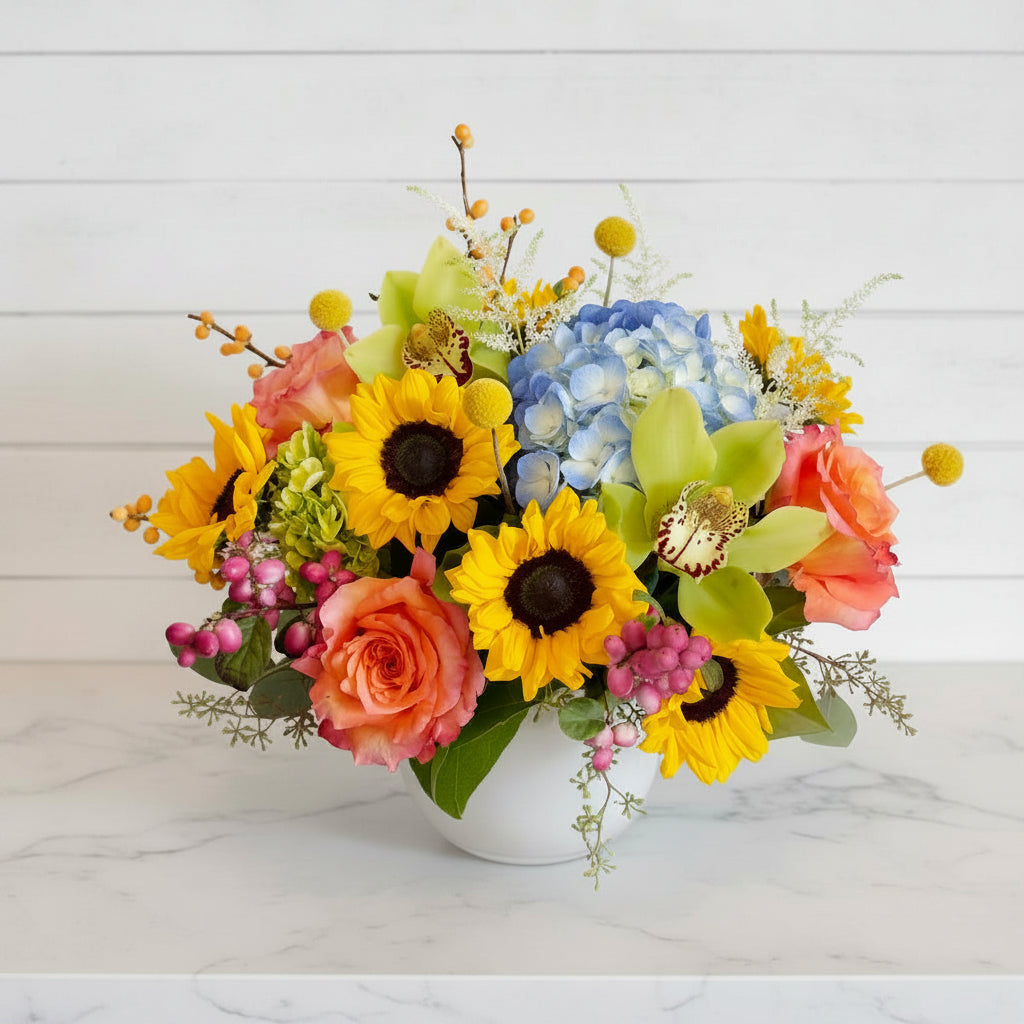 Colorful flower arrangement with sunflowers, roses, and orchids on a white background