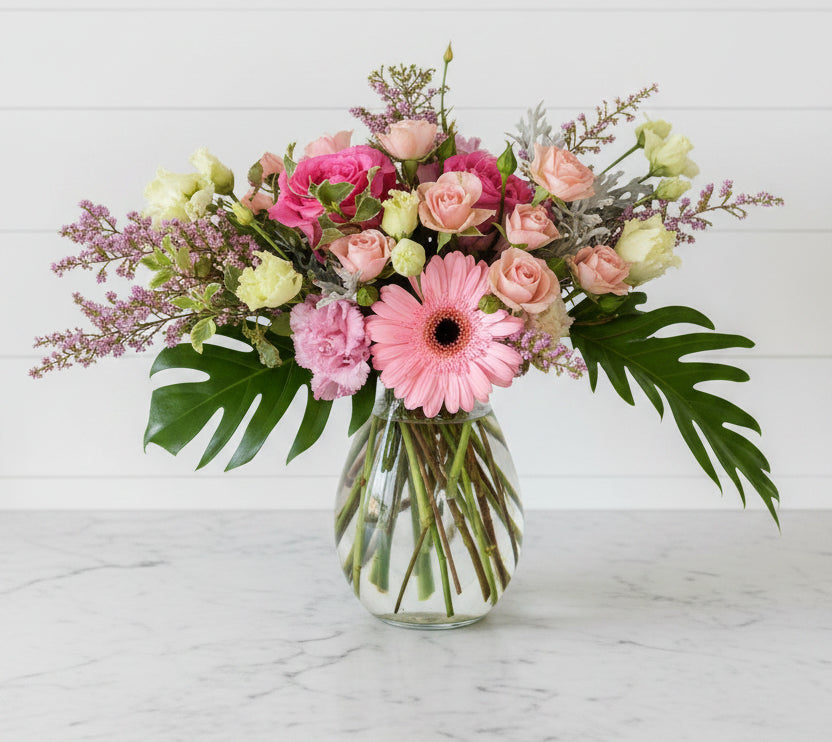 Bouquet of pink and green flowers in a clear vase on a white background