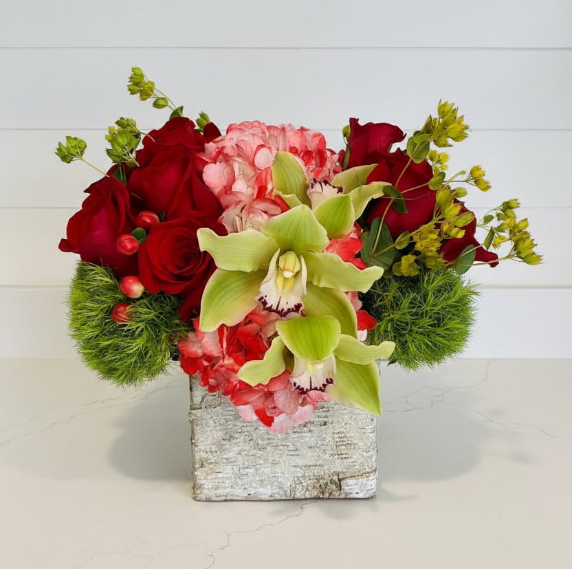Colorful flower arrangement in a glass vase on a table with a home interior background
