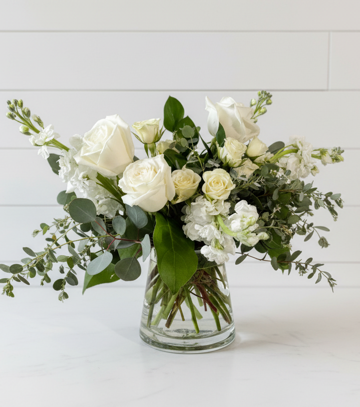 Bouquet of white and green flowers in a clear vase on a white background