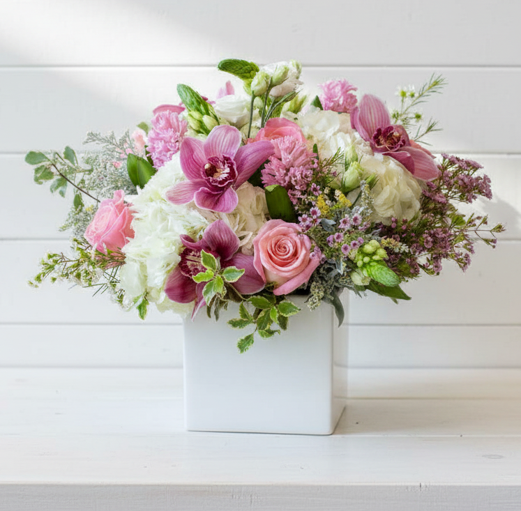 Bouquet of pink and white flowers in a white box on a light wooden background