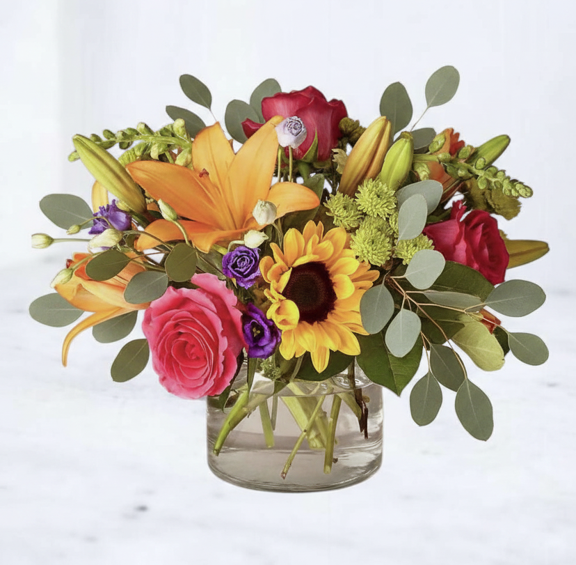 Colorful flower arrangement in a clear vase on a light background
