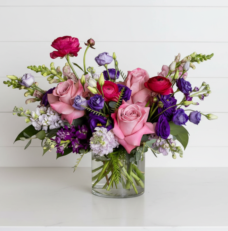 Bouquet of colorful flowers in a clear vase on a white background